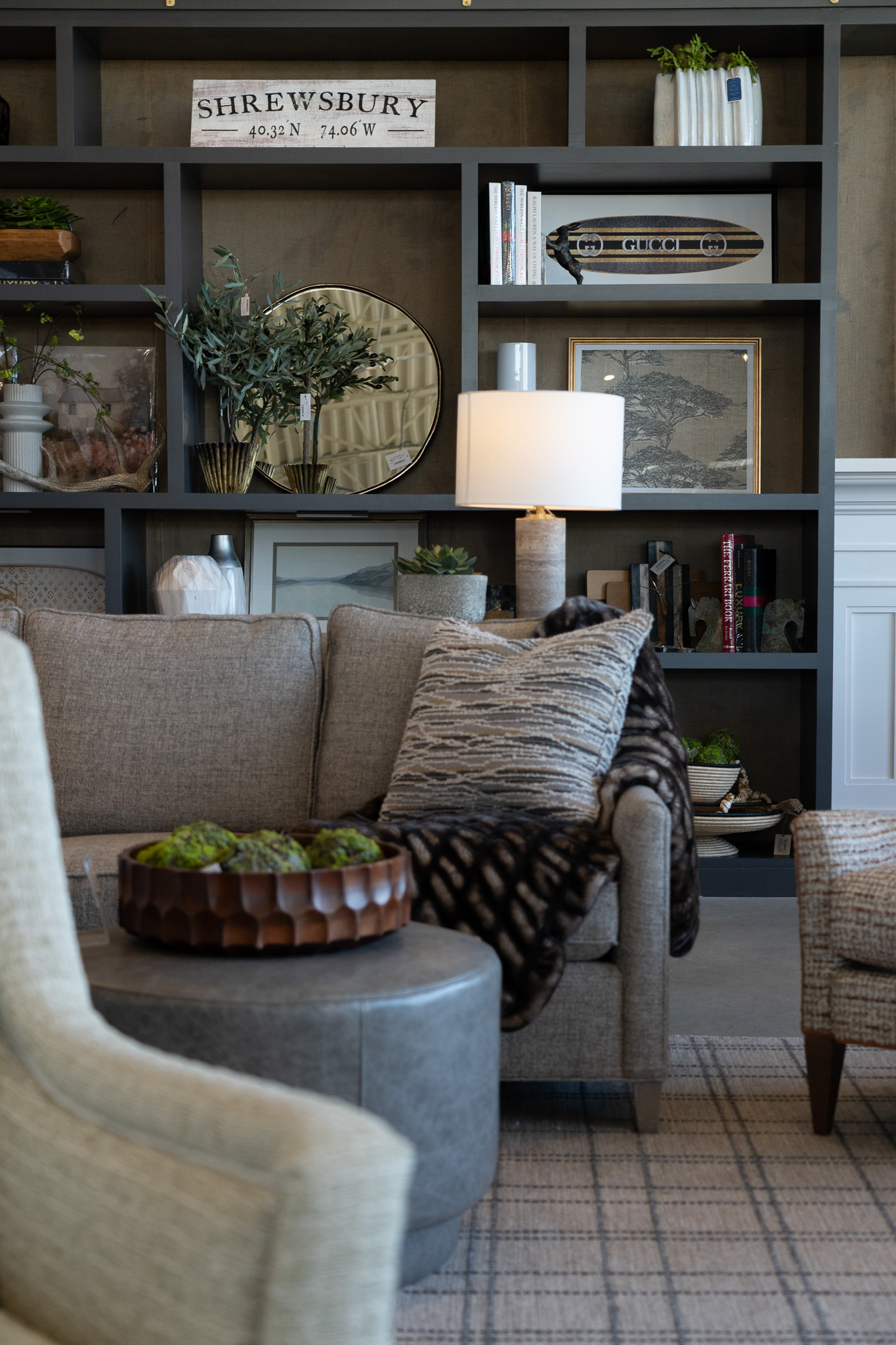 Grey sofa and white lamp in front of decor options at Platypus Home